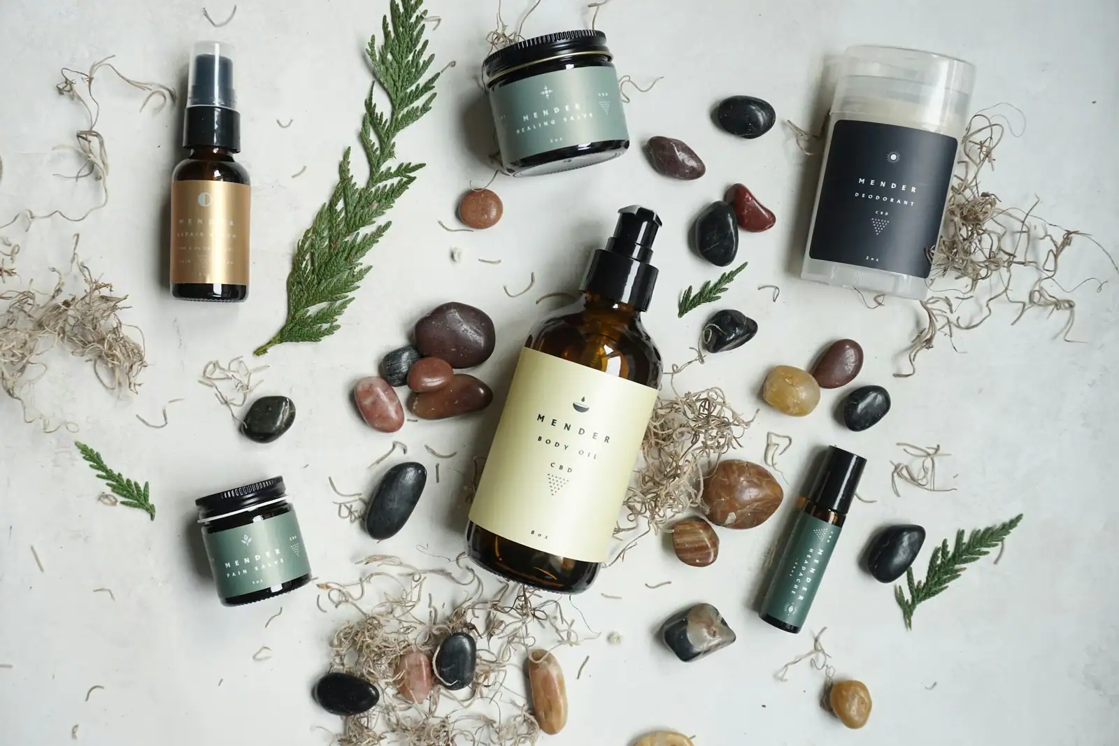 Skin care bottles among plant sprigs and stones