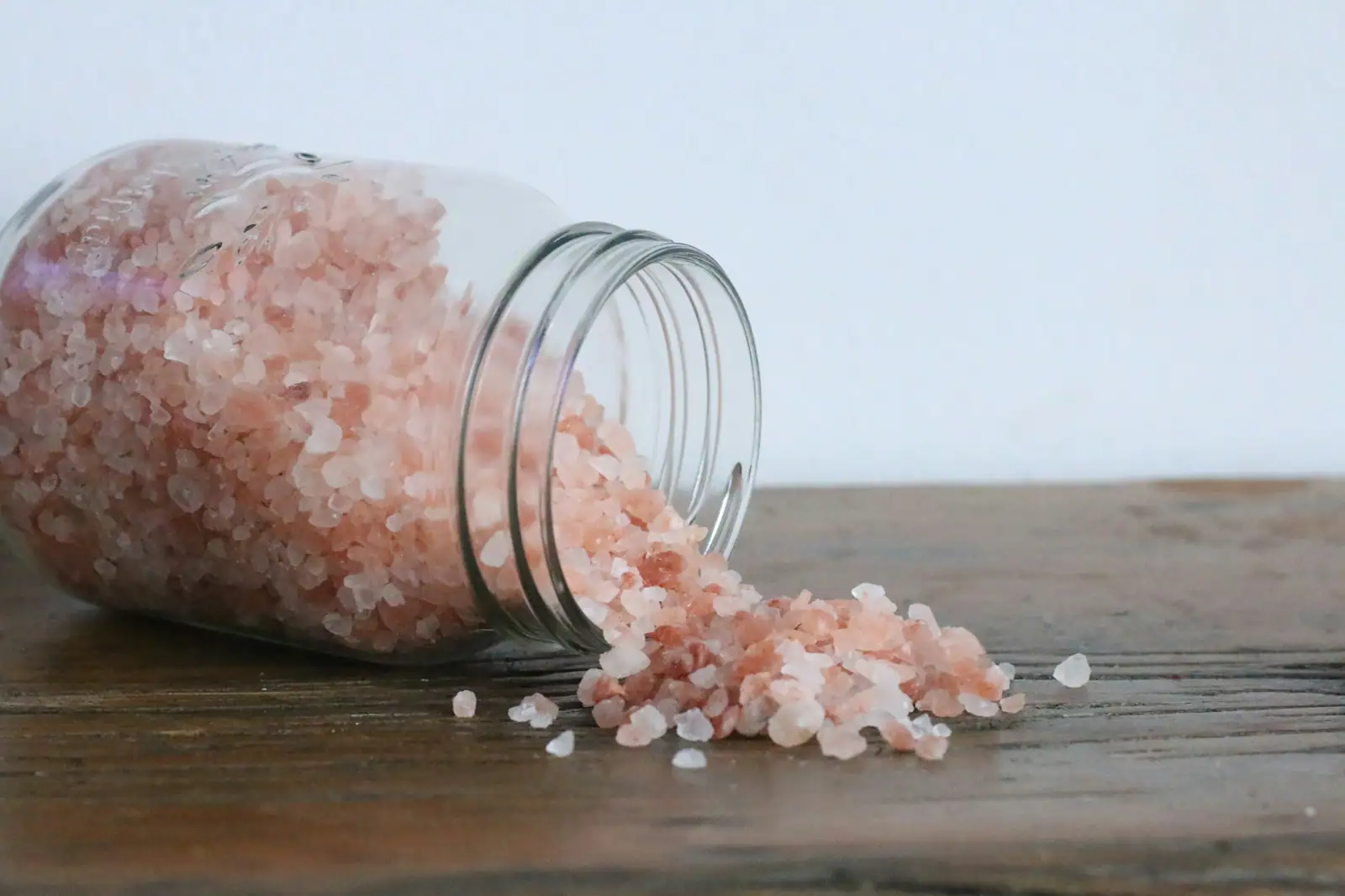 Pink salt crystals spilling from a jar
