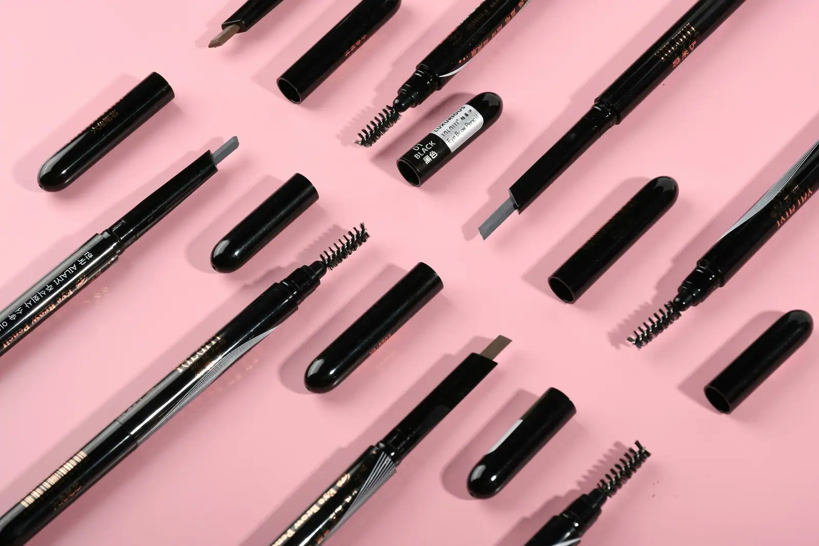Brow pencils and brushes on a pink background