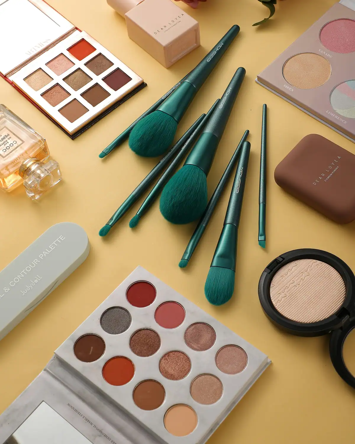 Eyeshadow palette and green-handled makeup brushes