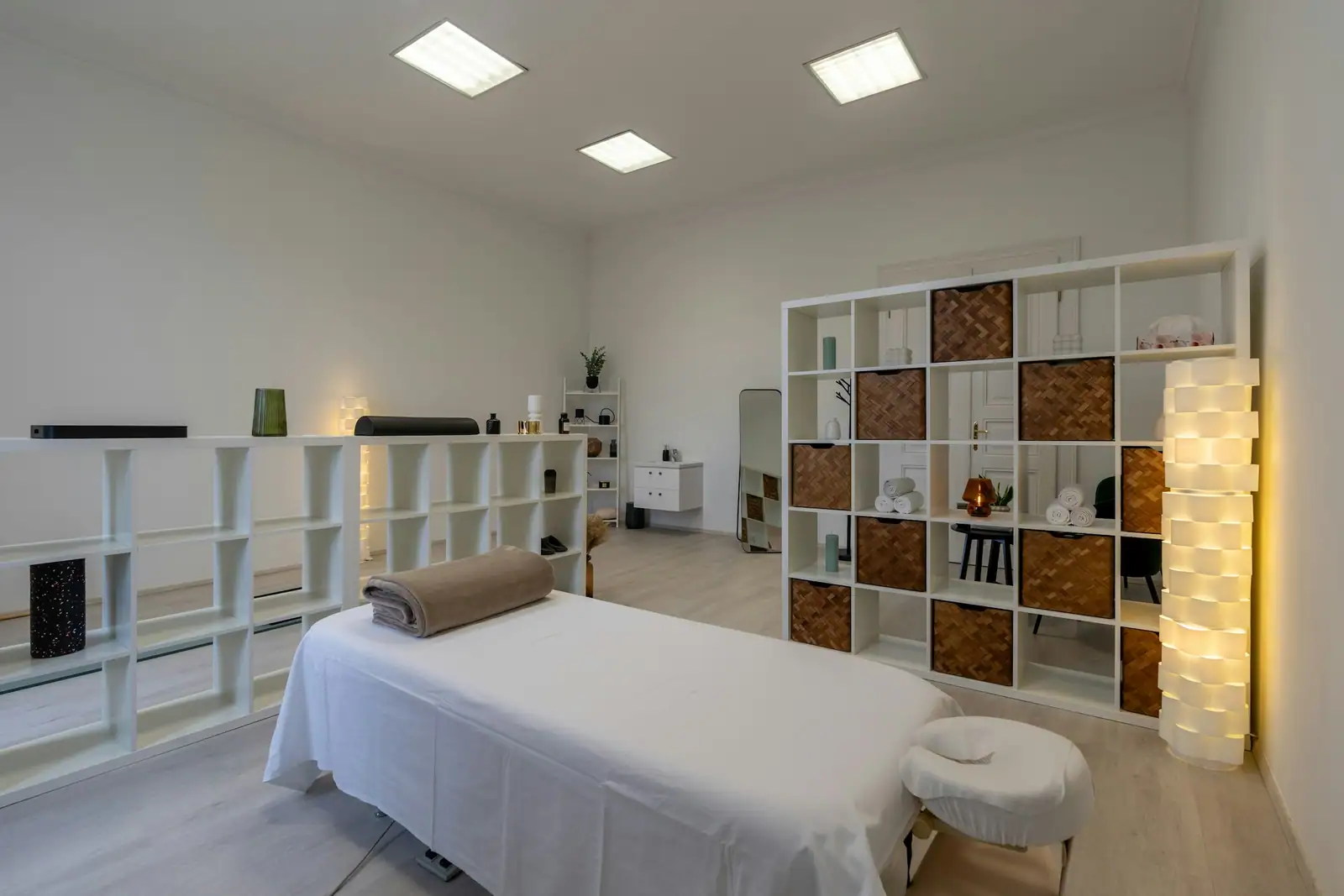 A bright massage room with white shelves