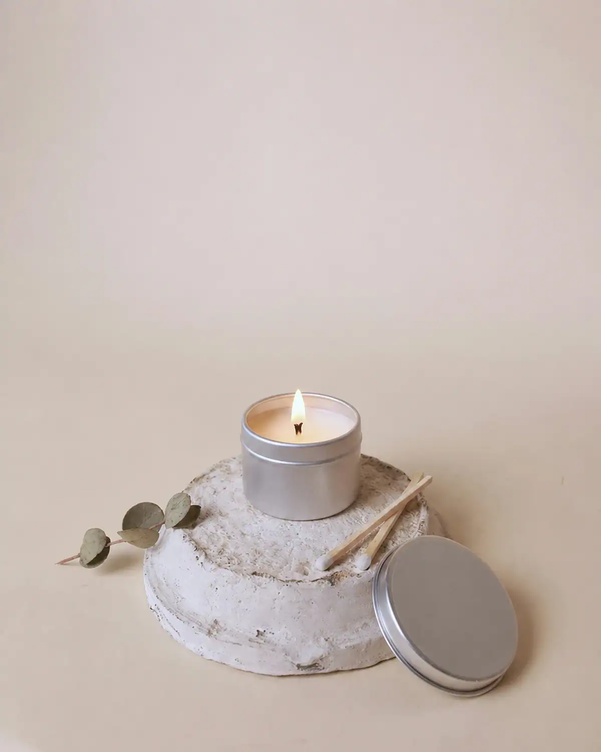 A lit candle and a eucalyptus sprig on a stone stand