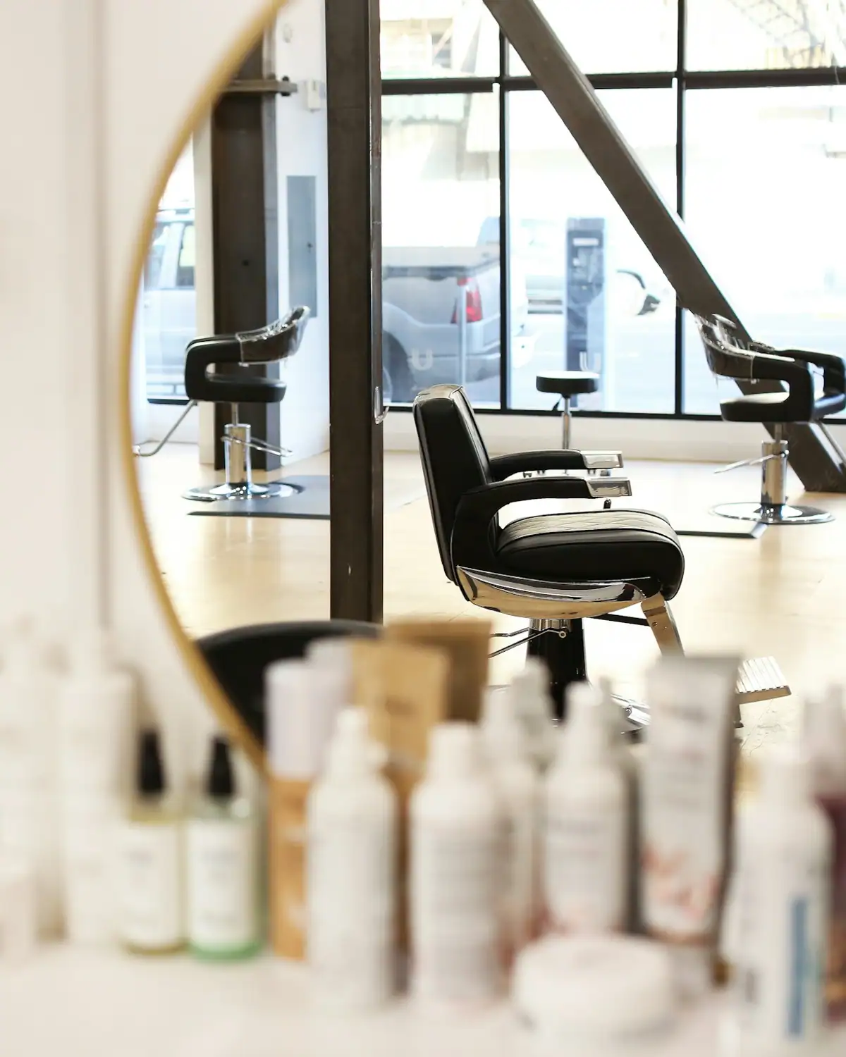 Round mirror, hair care products and a salon chair