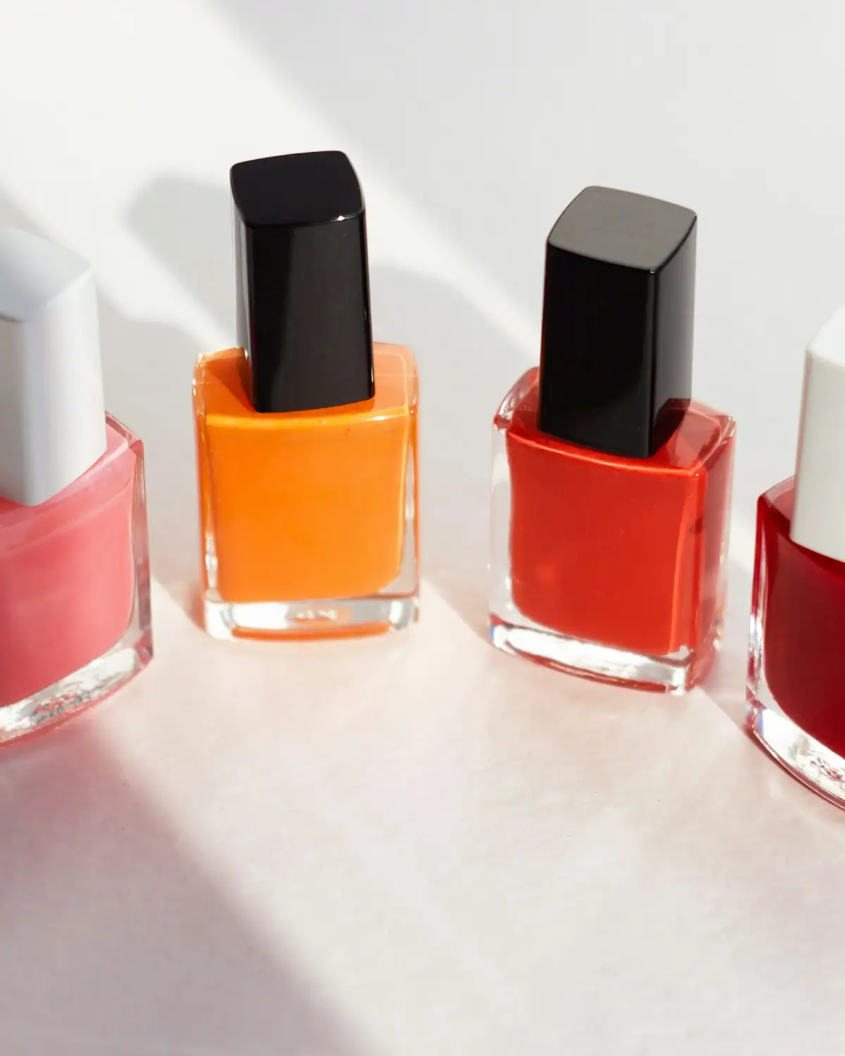 Coral, orange and red nail polish bottles