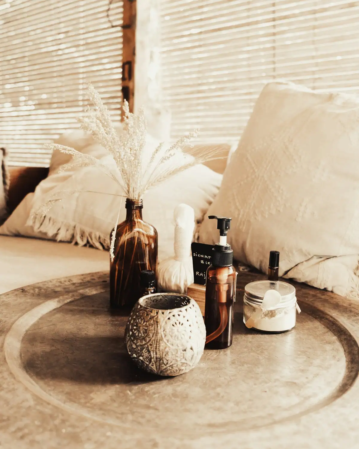 Brown bottles, dried herbs and cream cushions on a tray